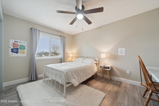 bedroom with a textured ceiling, wood finished floors, and baseboards