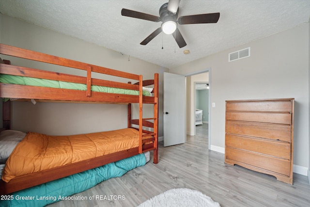 bedroom featuring a textured ceiling, wood finished floors, visible vents, and baseboards