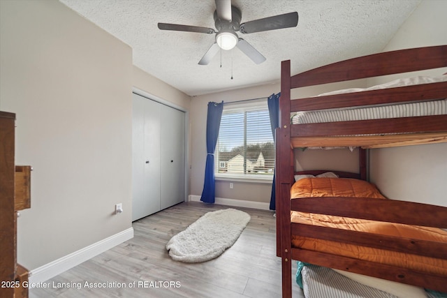 bedroom with a textured ceiling, baseboards, and wood finished floors