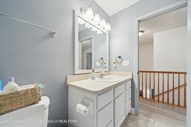 half bath with toilet, a textured ceiling, and vanity