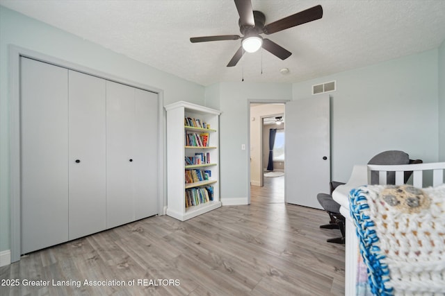 unfurnished bedroom with light wood-type flooring, a textured ceiling, visible vents, and a closet