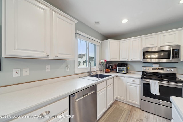 kitchen featuring white cabinets, stainless steel appliances, a sink, and light countertops