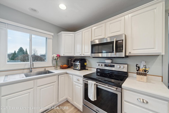 kitchen featuring light countertops, appliances with stainless steel finishes, a sink, and white cabinetry