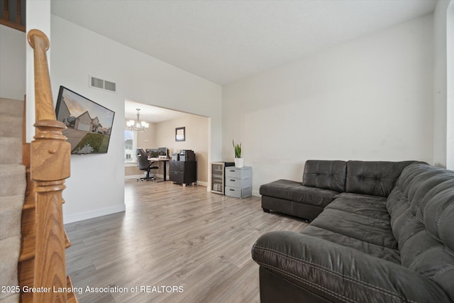 living area featuring an inviting chandelier, baseboards, visible vents, and wood finished floors