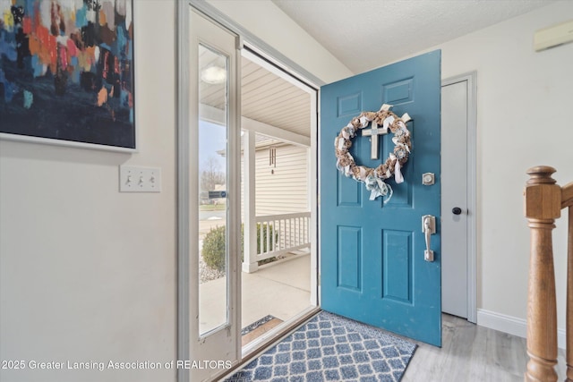 foyer entrance featuring baseboards and wood finished floors