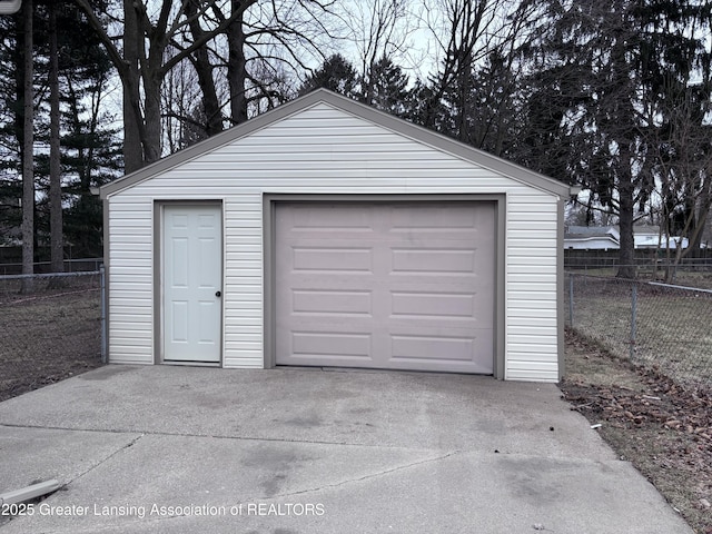 detached garage featuring fence and concrete driveway