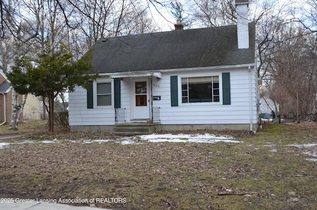 view of front facade with roof with shingles and a chimney