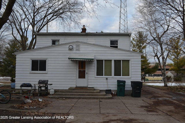 back of property featuring entry steps and a chimney