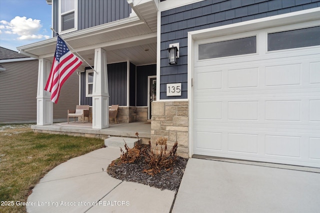 property entrance with a garage, stone siding, a porch, and board and batten siding