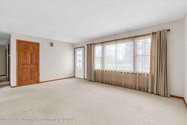 unfurnished room featuring baseboards and light colored carpet