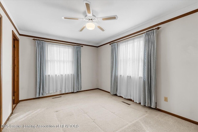 carpeted empty room featuring baseboards, visible vents, a ceiling fan, and ornamental molding