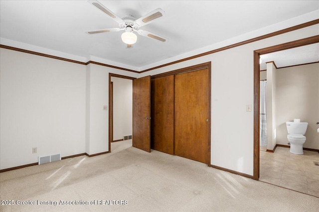 unfurnished bedroom featuring ornamental molding, a closet, visible vents, and light carpet