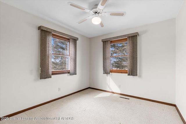 carpeted empty room with ceiling fan, visible vents, and baseboards