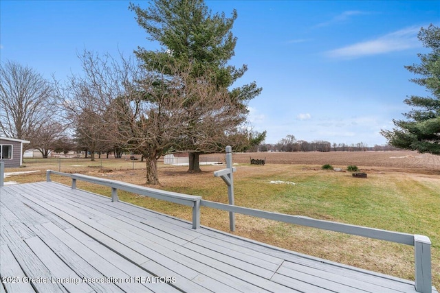 wooden terrace with a rural view and a yard