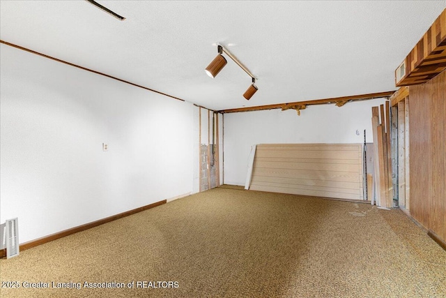 unfurnished living room with a textured ceiling, light carpet, visible vents, baseboards, and rail lighting