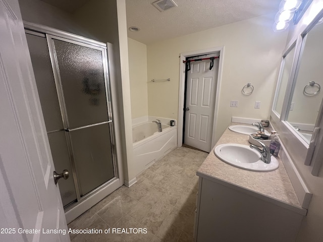 full bathroom featuring visible vents, a stall shower, a sink, a textured ceiling, and a garden tub