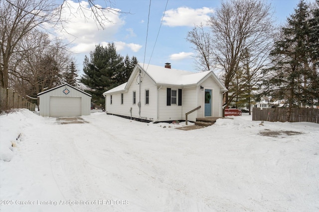 view of front of home with a garage, a chimney, an outbuilding, and fence