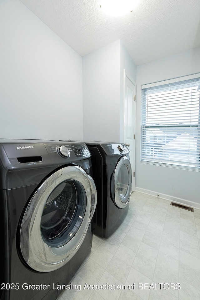 washroom featuring a textured ceiling, laundry area, visible vents, baseboards, and independent washer and dryer