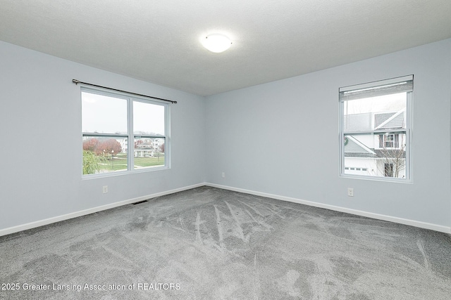 spare room featuring a textured ceiling, baseboards, and carpet flooring