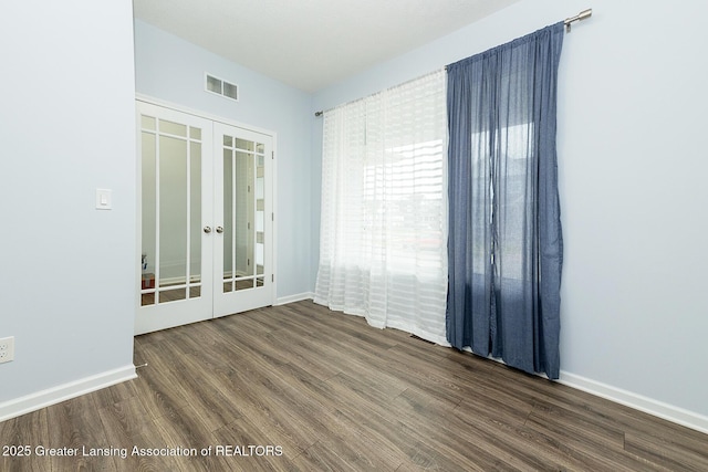 unfurnished room featuring french doors, visible vents, baseboards, and wood finished floors