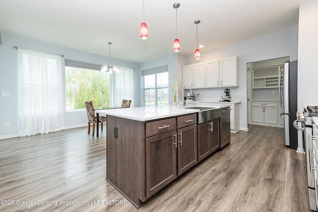 kitchen featuring stainless steel appliances, a sink, light countertops, and light wood-style floors