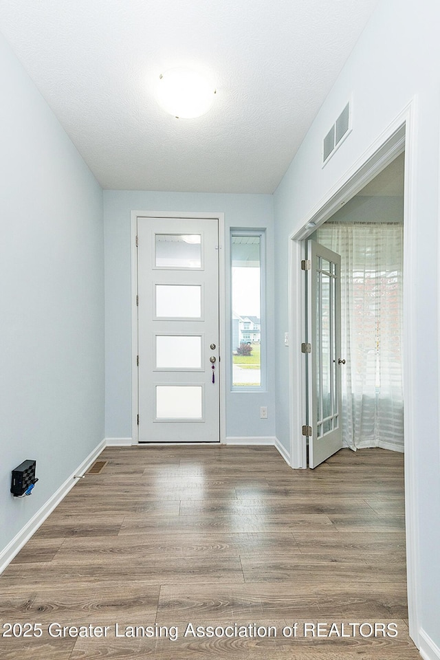 foyer entrance featuring wood finished floors, visible vents, and baseboards