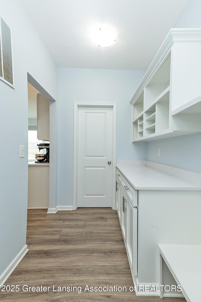 kitchen with dark wood-style floors, open shelves, light countertops, white cabinets, and baseboards