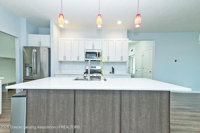 kitchen with stainless steel appliances, a spacious island, a sink, and white cabinetry