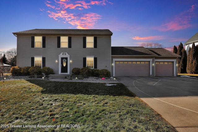 colonial inspired home with a garage, a front yard, and driveway