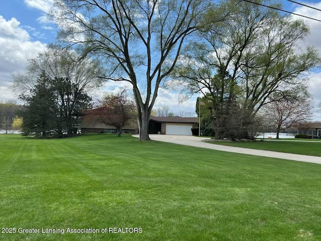 view of yard featuring an attached garage and concrete driveway