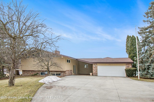 view of front of house with brick siding, a chimney, concrete driveway, a garage, and a front lawn