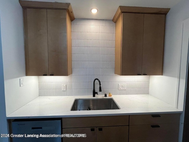 kitchen with tasteful backsplash, light stone counters, gray cabinets, a sink, and recessed lighting