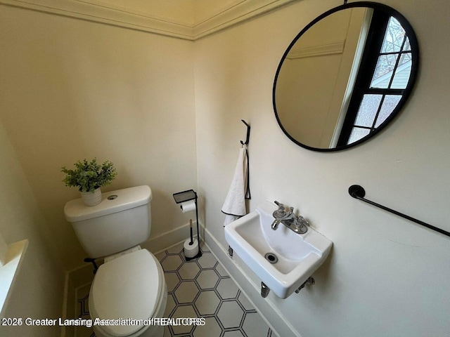 half bath with a sink, toilet, and baseboards