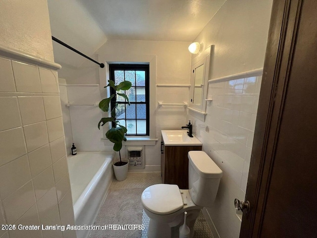 bathroom featuring wainscoting, toilet, heating unit, vanity, and tile walls