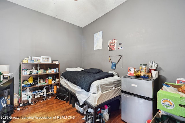 bedroom with wood finished floors and freestanding refrigerator