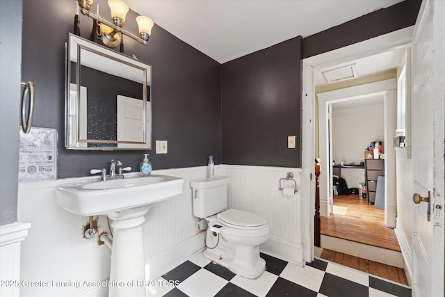 half bathroom featuring a wainscoted wall, toilet, and tile patterned floors