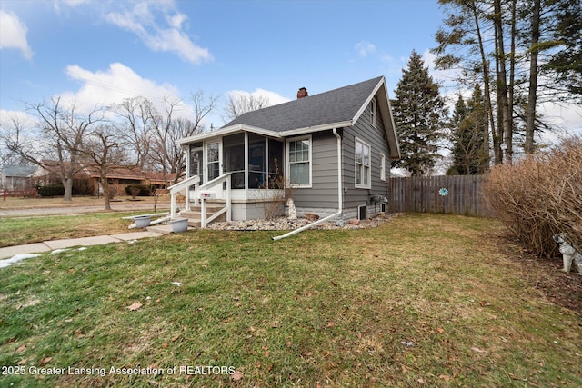 bungalow featuring a sunroom, fence, a chimney, and a front lawn