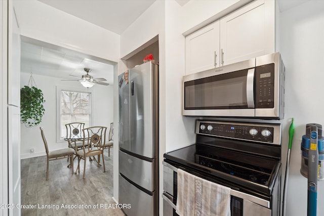 kitchen with appliances with stainless steel finishes, white cabinetry, ceiling fan, and light wood-style flooring