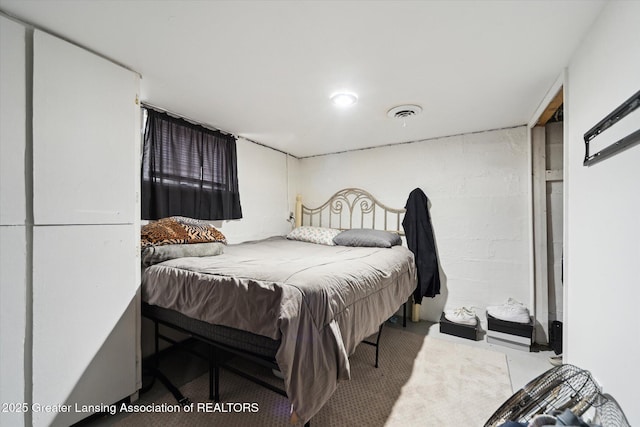 bedroom featuring concrete block wall, visible vents, and concrete flooring