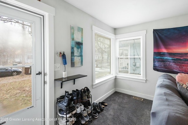 interior space with visible vents, dark colored carpet, a wealth of natural light, and baseboards