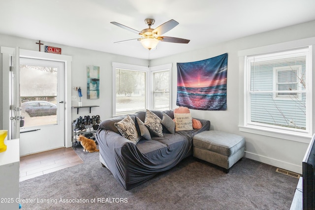 carpeted living area with baseboards, visible vents, and a ceiling fan