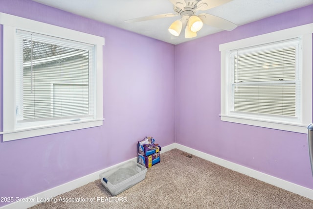 carpeted spare room featuring visible vents, ceiling fan, and baseboards