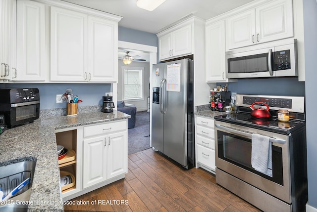 kitchen featuring light stone countertops, appliances with stainless steel finishes, white cabinets, and dark wood-style flooring