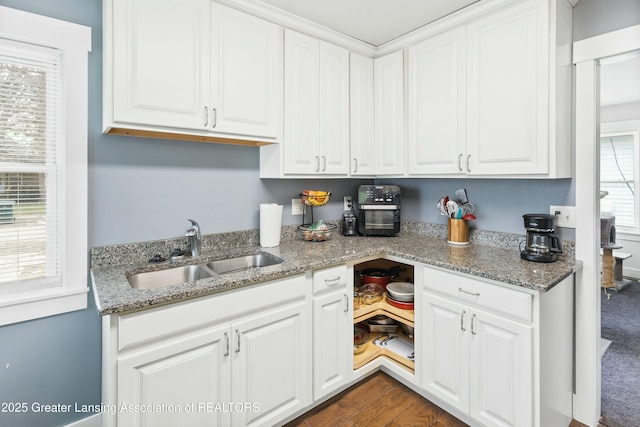 kitchen featuring dark wood-style flooring, a sink, light stone countertops, and white cabinets