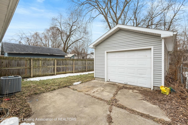 detached garage with fence, driveway, and central AC unit