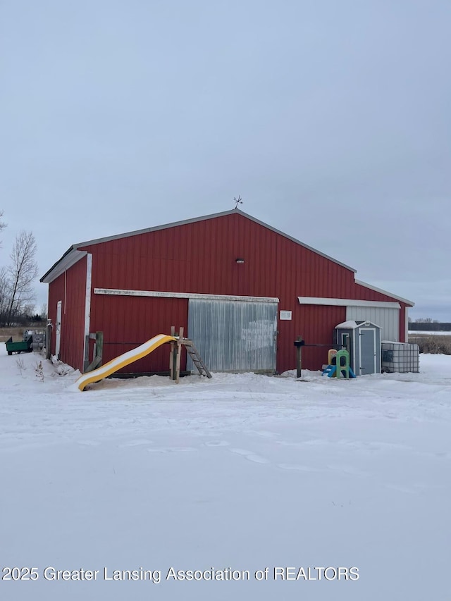 snow covered structure with an outbuilding and an outdoor structure