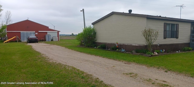 11173 W Bennett Rd, Sumner, MI 48889 - view of side of home with dirt driveway, a garage, a yard, and an outdoor structure