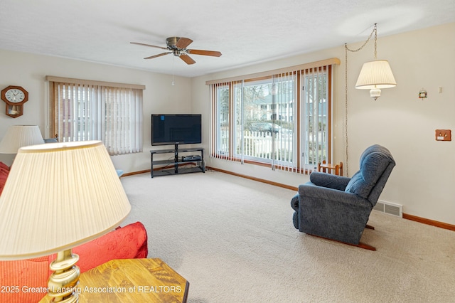 living room featuring carpet, a healthy amount of sunlight, visible vents, and baseboards