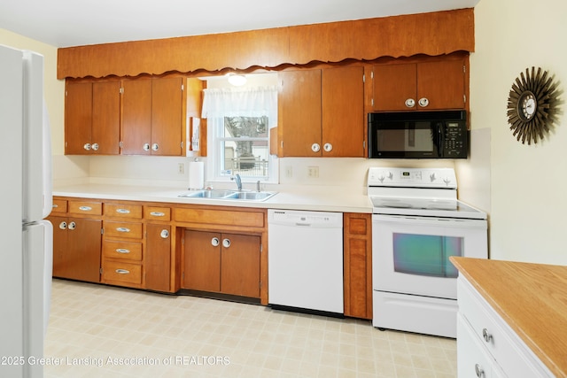 kitchen with white appliances, light countertops, a sink, and brown cabinetry