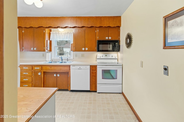 kitchen with white appliances, a sink, baseboards, light countertops, and brown cabinetry